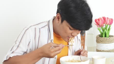 Asian-Young-Man-Enjoying-Eating-Hot-Boiled-Noodle-Using-Chopstick-And-Spoon-With-Happy-Expression