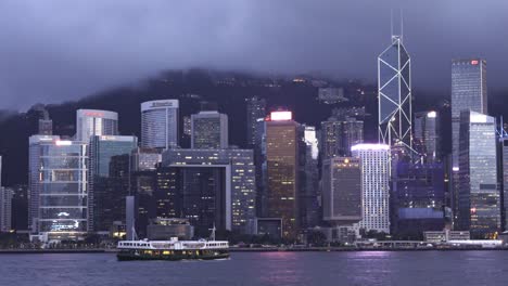 Eine-Stationäre-Weitwinkelaufnahme-Eines-Passagiertransportschiffs-Der-Cruising-Star-Ferry-Entlang-Des-Victoria-Harbour-An-Einem-Bewölkten-Tag-Entlang-Der-Gebäude-Und-Wolkenkratzer-In-Hongkong