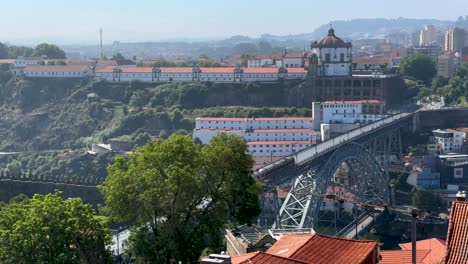 Pintoresca-Vista-Panorámica-De-Un-Tren-Que-Cruza-El-Puente-Dom-Luis-I-Y-El-Monasterio-De-Santo-Agostinho-Da-Serra-Do-Pilar,-Conocido-Como-Monasterio-De-Serra-Do-Pilar-En-Porto,-Portugal