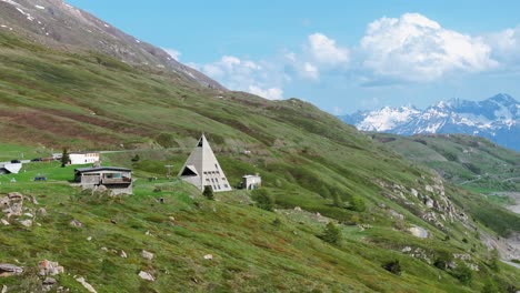 A-beautiful-aerial-shot-showcasing-various-buildings-on-the-lush-green-hillside-of-Mont-Cenis-with-mountains-in-the-background