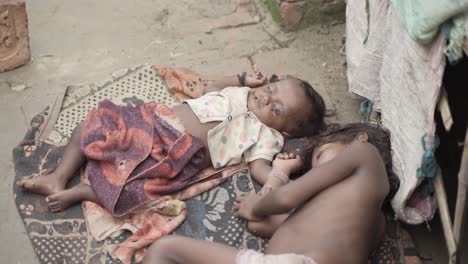 Two-kids-are-sleeping-outside-in-the-open-sky-and-flies-are-flying-around