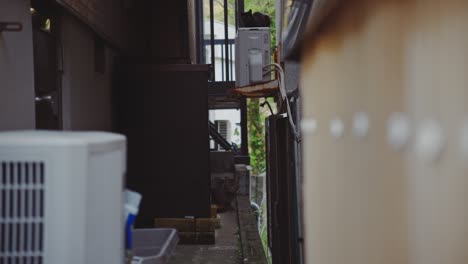 Un-Callejón-Estrecho-Entre-Casas-En-Saikazaki,-Wakayama,-Japón,-Con-Varias-Unidades-De-Aire-Acondicionado-Y-Una-Escena-Callejera-Urbana.