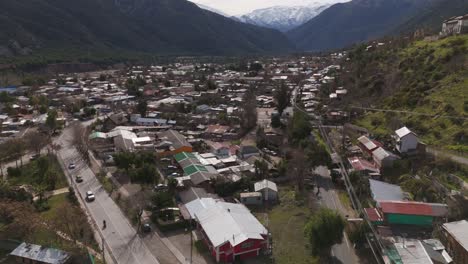 Aerial-view-of-San-José-de-Maipo,-a-peaceful-town-nestled-in-a-scenic-valley-with-rooftops-and-mountains-in-view