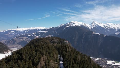 Skilift-In-Den-österreichischen-Alpen,-Aufgenommen-Mit-Einer-Drohne,-Die-Die-Grünen-Bäume-Und-Schneebedeckten-Berge-Im-Hintergrund-Einfängt