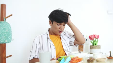 Un-Joven-Asiático-Se-Sorprende-Al-Comer-Fideos-Picantes-Y-Tratar-De-Refrescarse-La-Boca-Con-La-Mano-Y-Bebiendo-Agua.