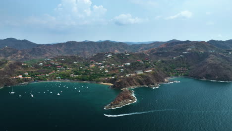 Aerial-view-away-from-boats-on-the-coast-of-Flamingo-Guanacaste,-in-Costa-Rica