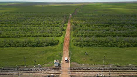 Un-Vehículo-Blanco-Circula-Por-Un-Camino-De-Tierra-En-El-Campo-De-Kazajstán,-Asia-Central.-Un-Dron-Vuela-Hacia-Adelante.