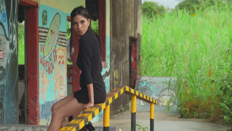 A-young-Latina-in-red-heels-enjoying-a-skate-park-warehouse-sitting-on-the-railings