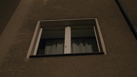 Looking-up-at-curtained-window-of-building-at-night