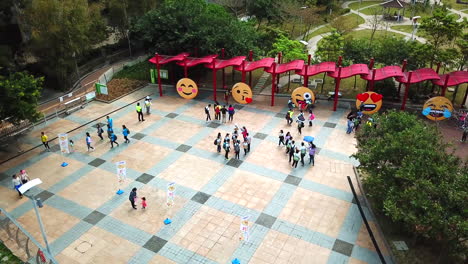 Aerial-Footage,-People-walking-in-Garden-with-Emojis-on-it