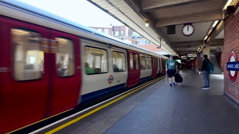 Tren-Rojo-Del-Metro-De-Londres-Llegando-A-Una-Estación-Con-Gente-Esperando-En-El-Andén