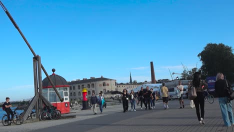 Hermosas-Imágenes-De-Personas-Caminando-En-Los-Muelles-De-Un-Puerto-En-Tallin,-Estonia,-En-Cámara-Lenta-Y-Resolución-4k-Durante-Un-Día-De-Verano-Cuando-El-Sol-Brilla-Y-El-Cielo-Azul-De-Fondo-Y-Una-Prisión.