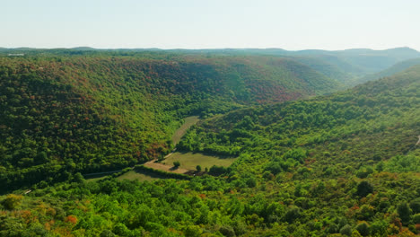 Forest-fire-risk-in-a-exotic-valley-with-a-river-and-green-hills,-sunny-day---aerial-view