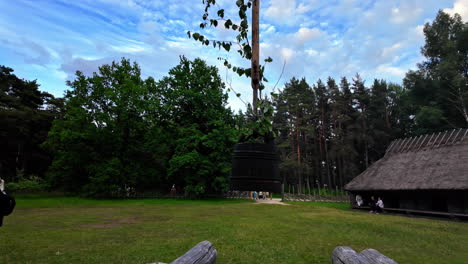 Camera-reveals-the-Estonian-Open-Air-Museum-with-visitors-walking-in-slow-motion,-panoramic-view