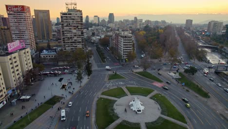 Dolly-in-flyover-of-Plaza-Baquedano,-now-Plaza-de-la-Dignidad-in-downtown-Santiago,-Chile,-sunset-in-the-background