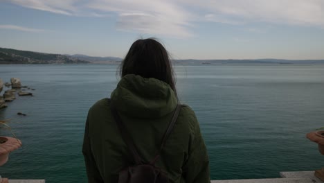 Young-brunette-woman-looking-at-the-view-of-Trieste-gulf-coastline,-Italy