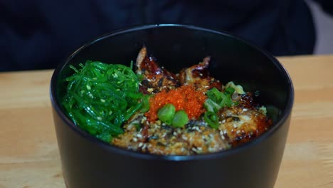 Popular-Japanese-rice-bowl-dish,-Unadon,-grilled-eel-glazed-with-a-thick,-sweet-soy-flavoured-sauce-on-top-of-steamed-rice,-pair-with-seaweed-salad-and-fish-roes