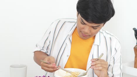 Asian-Man-Enjoying-Eating-Noodles-With-Chopsticks-At-Home