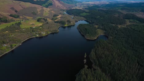 Aerial-Top-Down-Pan-of-Loch-Ard-in-the-Loch-Lomond-and-Trossachs-National-Park,-Green-Pine-Forest-wrapping-around-the-water-shoreline,-Scottish-Highlands,-Scotland-on-sunny-summers-day