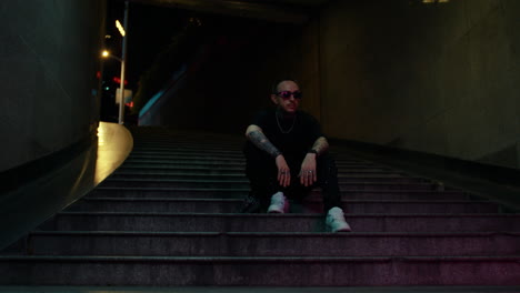 cool-guy-posing-on-stairs,-hanging-out-in-underground-subway-station,-green-lights