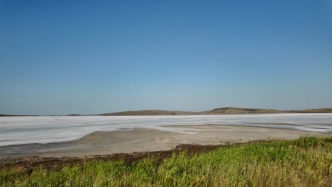 A-dry-lakebed-in-Crimea,-Russia,-with-a-clear-blue-sky-and-white-salt-deposits