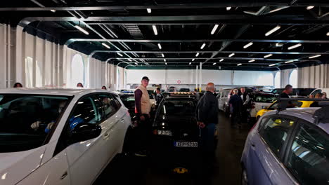 Cars-parked-on-a-ferry-deck,-passengers-standing-around,-heading-to-Zakynthos-in-Greece