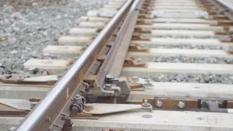 Close-up-of-railroad-tracks-showing-details-like-bolts-and-wooden-ties,-conveying-industry-and-travel