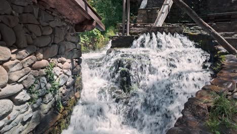 Sprudelndes-Wildwasser,-Das-Von-Einer-Rustikalen-Schleuse-Zu-Einer-Aus-Stein-Gebauten-Mühle-Stürzt