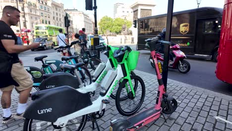 Un-Hombre-Desbloquea-Una-Bicicleta-De-Alquiler-En-Trafalgar-Square,-En-Londres,-Durante-Una-Mañana-Ajetreada.