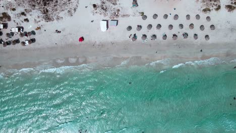 Das-Bild-Ist-Eine-Luftaufnahme-Eines-Strandes-Mit-Kristallklarem-Wasser-In-Mahdia,-Wo-Die-Menschen-Verschiedene-Aktivitäten-Genießen