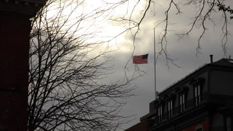 United-States-flag-flies-at-half-mast-against-grey,-cloudy,-winter-skies-4K