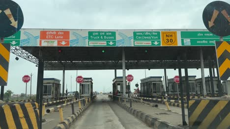 FASTag-technology-at-toll-plaza-or-toll-tax-station-in-india,-Car-passing-through-toll-booths-plaza-showing-automatic-payment-process