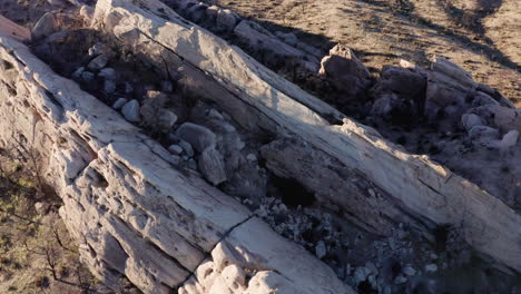 An-aerial-view-captures-the-rugged-beauty-of-Devil's-Punchbowl-rock-formations,-bathed-in-the-golden-glow-of-sunset