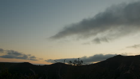 Farbenfroher-Sonnenuntergang-über-Dem-Bergkamm,-Während-Wolken-Durch-Den-Himmel-Ziehen