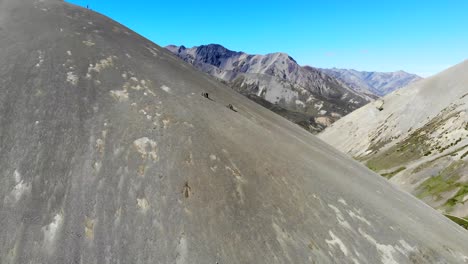 Two-mountain-bikers-push-up-scree-slope-in-the-South-Island-Mountains-in-New-Zealand