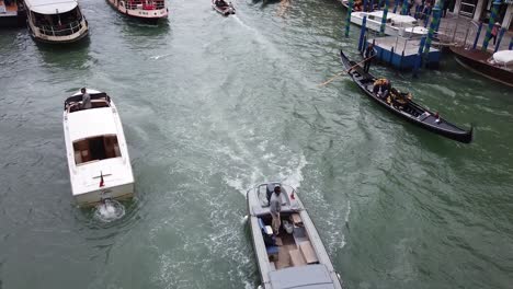 touring-lovers-in-gondola-at-Venice-canal,-high-angle-tracking-shot