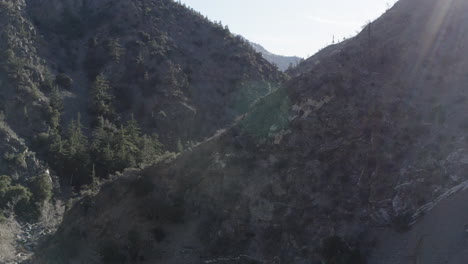 Sunlight-streaming-over-forested-hills-and-rugged-terrain-in-Devil's-Punchbowl