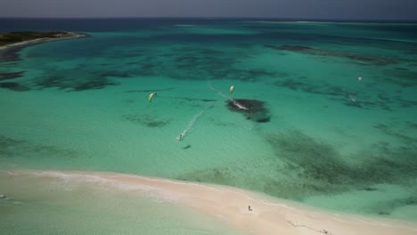 Turquoise-waters-with-kitesurfers-near-a-sandbar-at-cayo-de-agua,-aerial-view