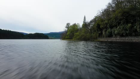 Niedriger-Flug-über-Das-Wasser-Des-Loch-Ard,-Grünen-Kiefernwald-Und-Straße-An-Bewaldeter-Küste,-Schottisches-Hochland,-Schottland