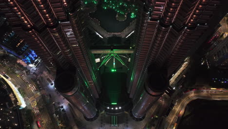 Aerial-view-tilting-backwards-over-the-Petronas-Twin-Towers,-night-in-Kuala-Lumpur