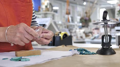 Shopkeeper-carefully-crafting-polymer-clay-earrings-at-workspace