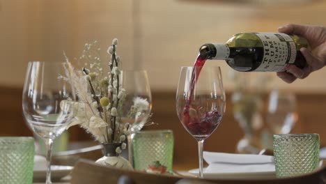 Closeup-on-a-hand-pouring-red-Australian-wine-into-a-glass-on-a-decorated-table