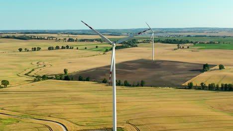 High-altitude-shot-capturing-wind-turbines-dispersed-in-wide-open-rural-fields,-emphasizing-the-integration-of-renewable-energy-solutions-in-agriculture