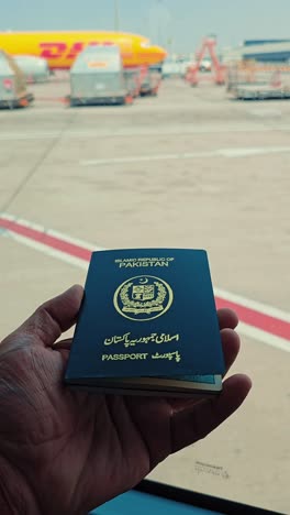 Primer-Plano-De-Un-Hombre-Que-Sostiene-El-Pasaporte-De-La-República-Islámica-De-Pakistán-En-El-Aeropuerto.