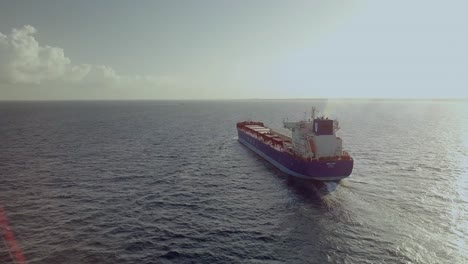 AERIAL---Huge-cargo-ship-in-the-ocean-at-sunrise-near-Cancun,-Mexico,-circle-pan