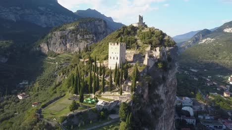 4K-Drohnenaufnahme-Einer-Alten-Burgfestung-Auf-Einem-Berggipfel-In-Einem-Kleinen-Dorf-Arco,-In-Der-Nähe-Von-Riva-Del-Garda,-Trentino