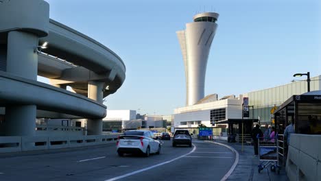 Autos,-Die-An-Der-Abholung-Vom-Hotel-Am-Flughafen-San-Francisco-Vorbeifahren,-Mit-Kontrollturm-Im-Hintergrund