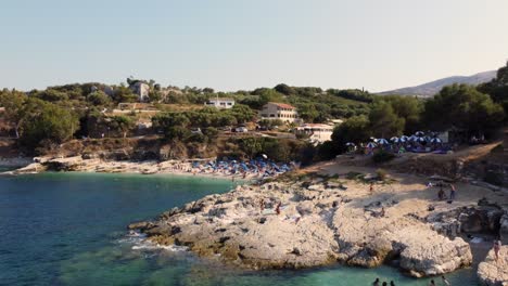 Reveladora-Panorámica-Aérea-De-La-Playa-De-Bataria-Llena-De-Turistas-En-Kassiopi,-Corfú,-Grecia