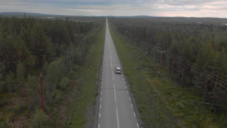 Drone-following-a-silver-volvo-in-northern-Swedish-landscape