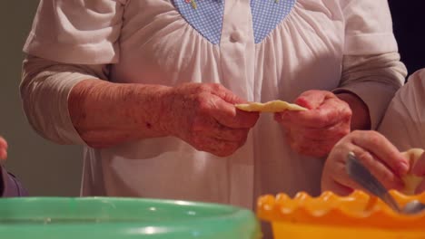 Grandmother-kneading-raw-dough-while-standing-up,-grandma-and-family-cooking